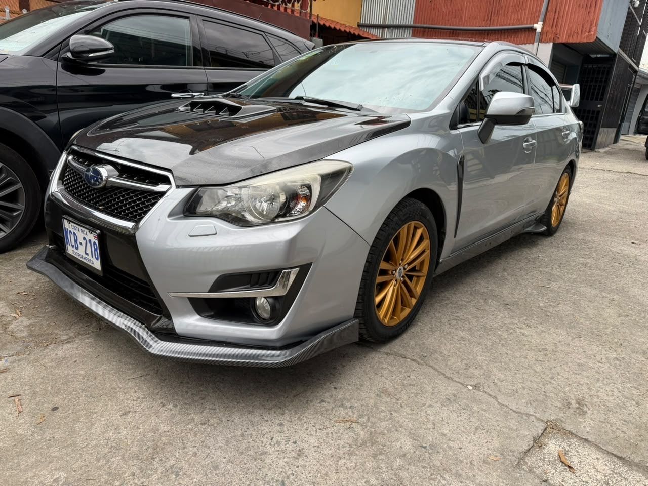 Subaru Impreza 2016 plateado de tres cuartos frontal, con capó de carbono y aros dorados