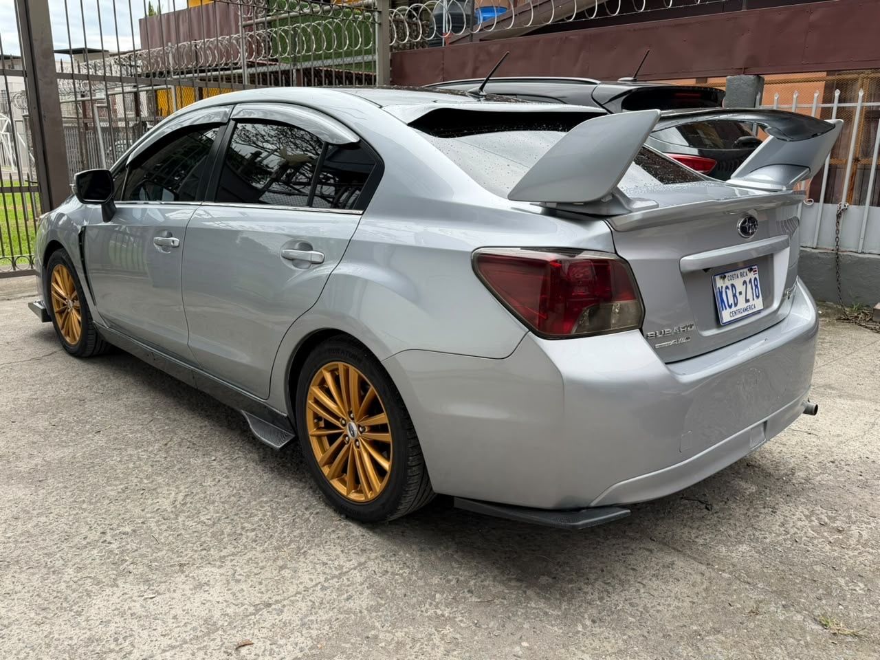 Vista trasera izquierda del Subaru Impreza Sport 2016 con alerón y aros dorados